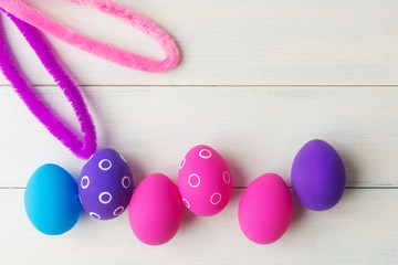 Bunny ears and decorative eggs on wooden background