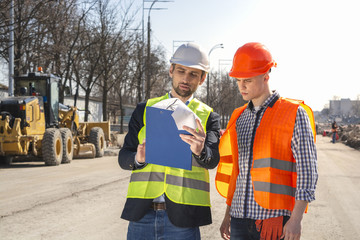 two men are builders workers are engineers at a construction site are looking at the drawings in helmets