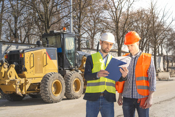 two men are builders workers are engineers at a construction site are looking at the drawings in helmets