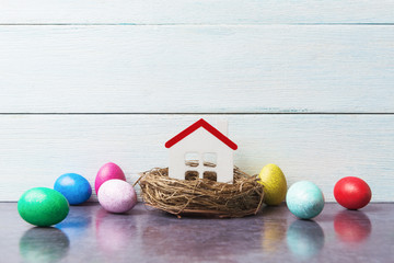 Easter concept with house model in nest and painted eggs