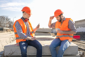 two man working engineers in helmets playing cards at a construction site