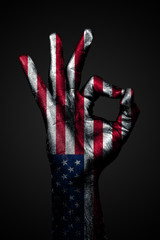 A hand with a drawn USA flag shows an ok sign on a dark background