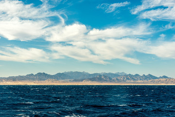 Fototapeta premium Seascape, view of the blue sea with high bald mountains in the background