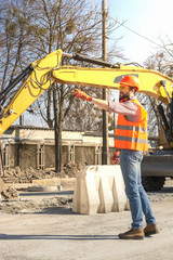 Fototapeta na wymiar male worker in a helmet at a construction site near an excavator