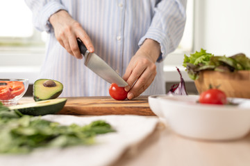 Obraz na płótnie Canvas woman prepares healthy vegetarian food, slicing vegetables