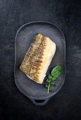 Gebratenes japanisches Skrei Kabeljau Fisch Filet mit Haut mit Wasabi Salat als Draufsicht auf...