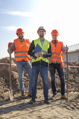 male workers engineers in helmets look into the camera and smile, at a construction site