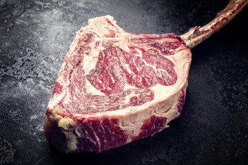 Raw dry aged wagyu tomahawk steak as closeup on an old rustic board with copy space