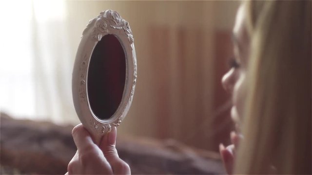 Close-Up Of Beautiful woman Looking At The Mirror and doing professional make-up with concealer and brush, Eye Makeup. 