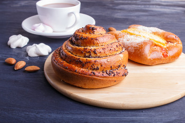 a cup of hot chocolate and buns  on black wooden background.