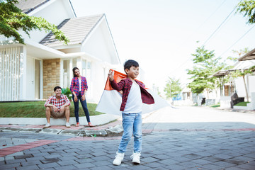 Obraz premium indonesian kid holding flag in front of his house. celebrating independence day