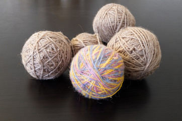 Home hobby.Four balls of gray thread and one color lie on a dark wooden table.
