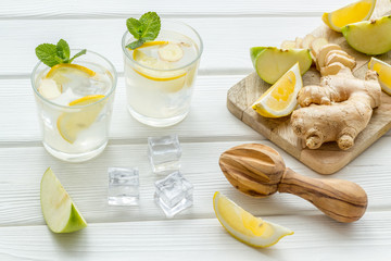 cold water with ice, ginger, mint, lemon and apple slices for summer healthy drink on white...