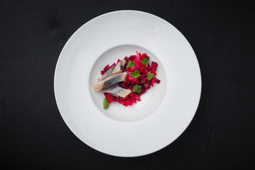 Beet with herring and parsley on a white plate. top view