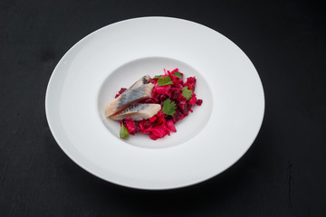 Beet with herring and parsley on a white plate