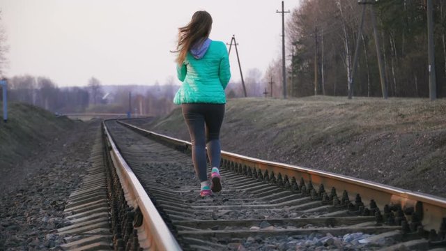 cute young girl walking on rails. missed the train. security breach