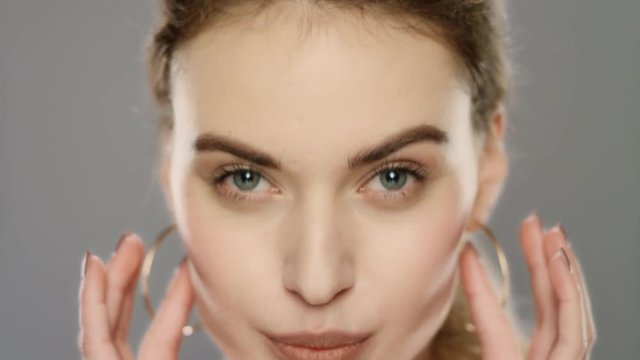 Young woman touching face skin in studio. Fashion model correcting makeup