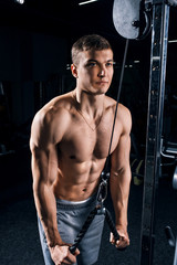 Fototapeta na wymiar Handsome muscular sportman working out, training arms in gym, pumping up muscles bicep and tricep with exercise machine. Sport, man physics, fitness and bodybuilding concept