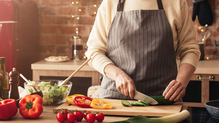 Mature woman cooking fresh vegetable salad in kitchen