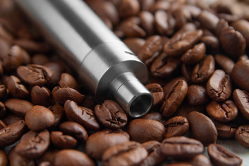 Stainless steel Vape device mod lies on the background of coffee beans
