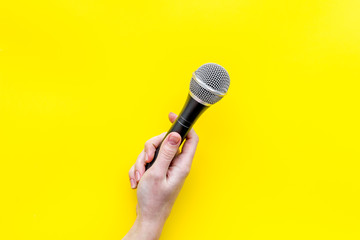 blogger, journalist or musician work space with microphone in hand on yellow background top view space for text
