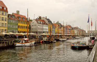 Panorama of north side of Nyhavn with colorful facades of old houses and old ships in the Old Town of Copenhagen, capital of Denmark.