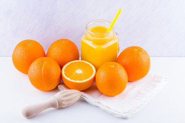 Fototapeta na wymiar Orange fruits and juice on white background. Citrus fruit for making juice with manual juicer. Oranges on white napkin. Mason jar with orange juice