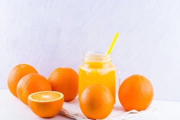 Orange fruits and juice on white background. Citrus fruit for making juice with manual juicer. Oranges on white napkin. Mason jar with orange juice