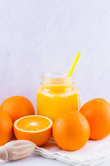Orange fruits and juice on white background. Citrus fruit for making juice with manual juicer. Oranges on white napkin. Mason jar with orange juice