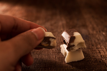 Hand with pieces of black and white chocolate.