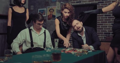 Beautiful women rob men. Girl takes all the chips and money, others threaten the men with a pistol.