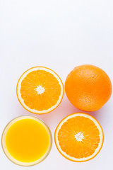 Orange fruits with juice, concept. Orange juice and halves of oranges on white background. Citrus for making juice. Whole and squeezed oranges and glass of juice