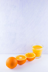 Orange fruits with juice, concept. Orange juice and halves of oranges on white background. Citrus for making juice. Whole and squeezed oranges and glass of juice