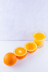 Orange fruits with juice, concept. Orange juice and halves of oranges on white background. Citrus for making juice. Whole and squeezed oranges and glass of juice
