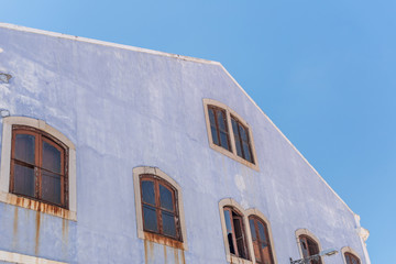 Old teal and white wall with rusty windows.