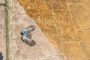 Sandals on a dry part of a concrete slab close to the water.