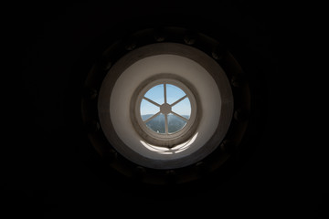 Round window sunny landscape outside, black interior