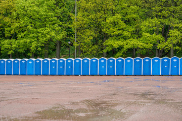 A row of portable toilets in front of a forest.