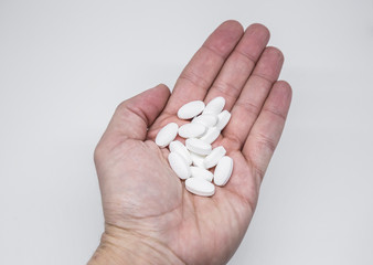 Medicine pills or capsules in elder hand