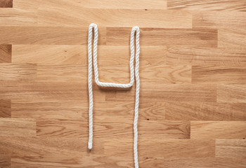 The letter H formed with white rope on a wooden table