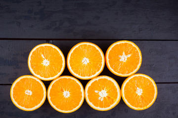 Oranges fruit on black wooden boards. Halves of juicy orange on black background. Orange fruit, citrus minimal concept. Top view, copy space