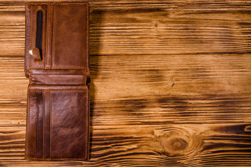 Opened brown leather wallet on wooden table. Top view
