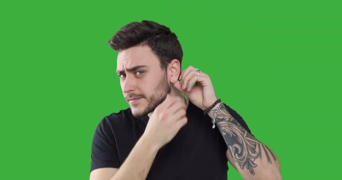Handsome man checking his earring and hairstyle 
