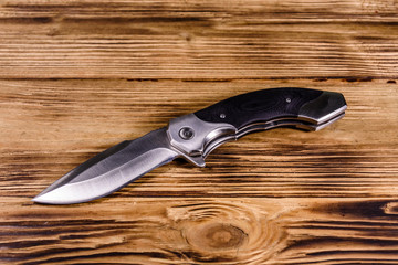 Opened folding knife on a wooden table