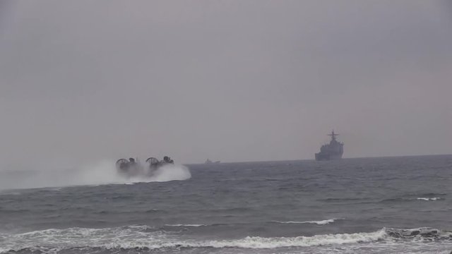 Military hovercraft speeding away in the ocean