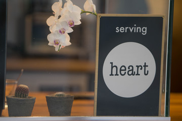 Naklejka premium Serving Heart store sign with succulents and orchid