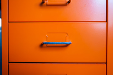 Filing cabinet with closed drawer, Orange metal colour, Administration and storage concept, closeup...
