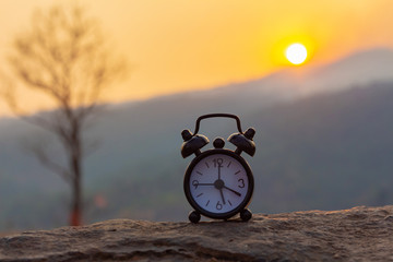 Clock on the stone at sunset nature background. vintage style