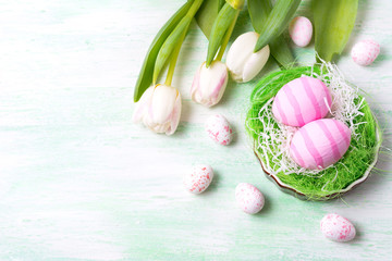 Easter pink eggs in the nest and white tulips, copy space.