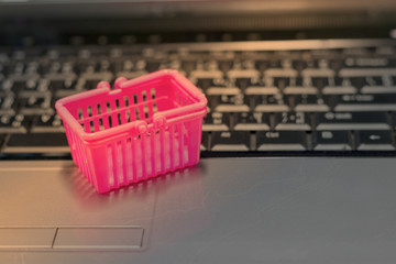 Basket shopping on laptop keyboard with light shining on the object. Consumer can buy products directly anywhere anytime from seller using web browser. Online shopping and e-commerce concept.